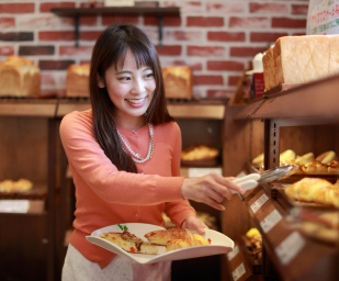 パン屋さんで女性がパンを選んでいる写真