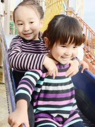 公園内の滑り台で子供二人が遊んでいる写真